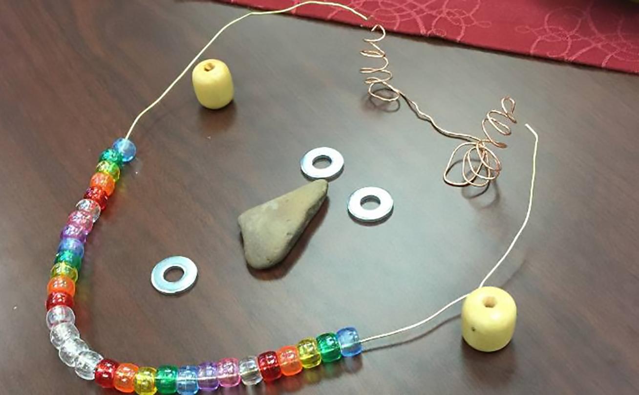 Necklace made from bead and rocks arranged to form a face